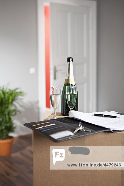 Champagner und ein Vertrag im Wohnzimmer mit Umzugskartons