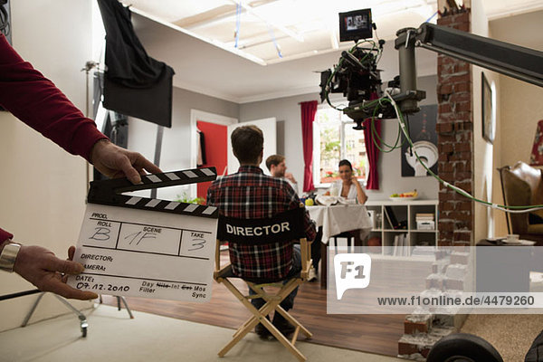 Ein Regisseur auf einem Filmset  der Schauspieler beim Aufführen einer Szene beobachtet.