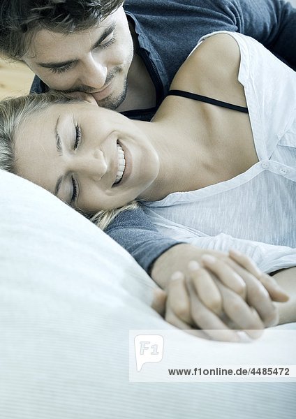 Junges Paar liegt Hand in Hand im Bett