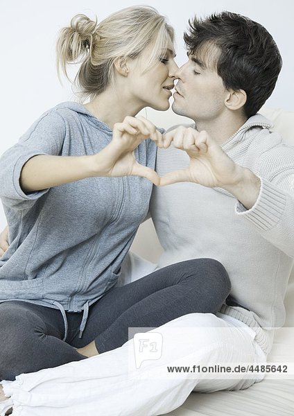 Young couple in love making heart with their hands