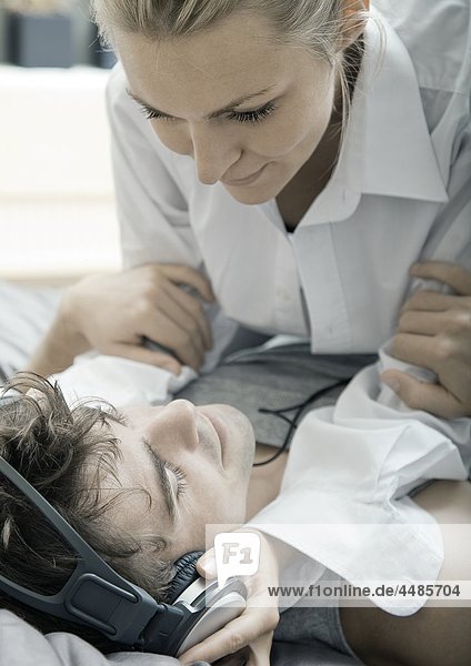 Young couple on bed listening to music with headphones