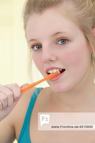 Young blond attractive woman with long hair brushing her hair with a tooth brush  in turquoise blue