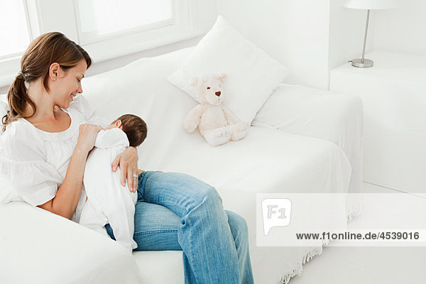 Mother breast feeding baby on sofa