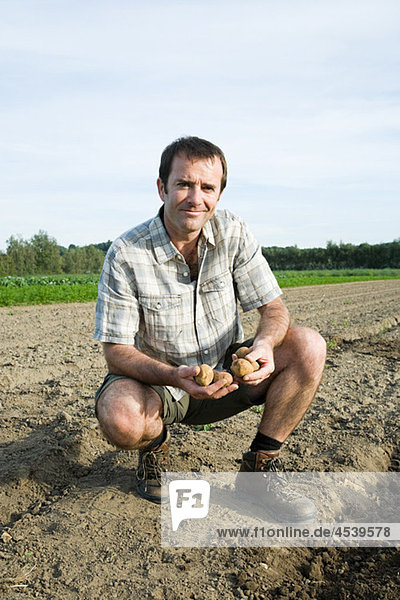 Mittelgroßer Mann mit Kartoffeln auf dem Feld