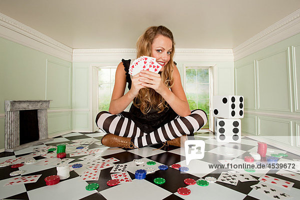 Junge Frau im kleinen Zimmer mit Spielkarten und Würfeln