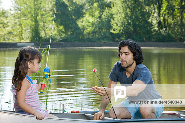 Father and daughter on rowboat with fishing rods