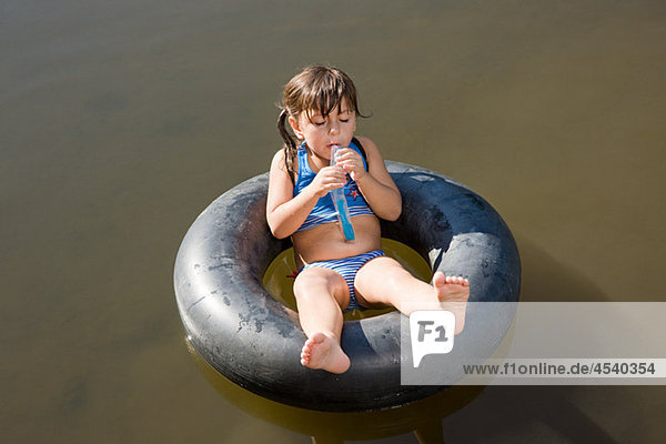 Girl eating Lolly auf aufblasbaren Ring in See