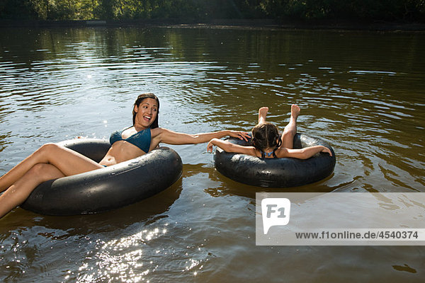 Mother and daughter in lake on inflatable rings