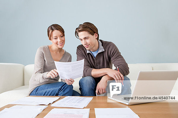 Young couple using computer and doing paperwork
