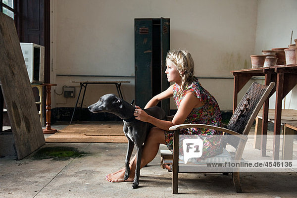 Junge Frau sitzt auf Stuhl mit Hund