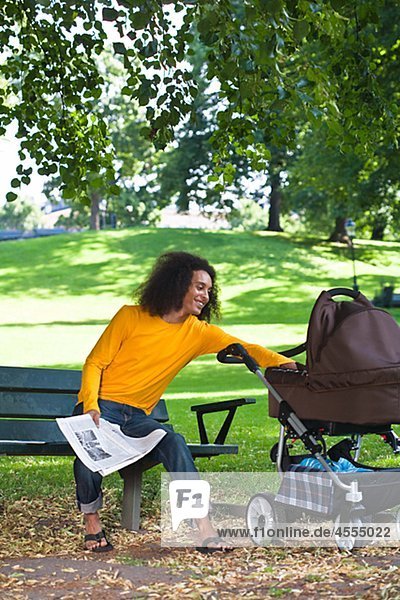 Young man with baby carriage sitting on bench