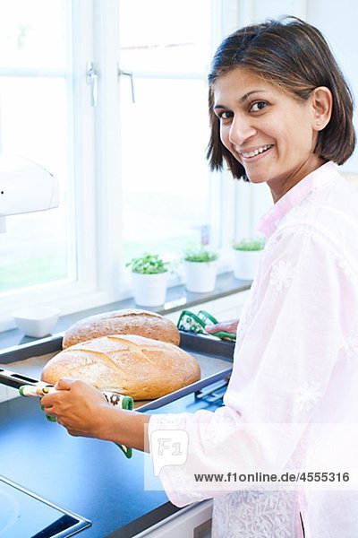 Portrait of Frau hält Brot auf Tablett in Küche
