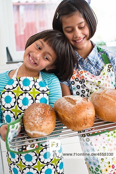 Zwei Mädchen halten frisches Brot in Küche