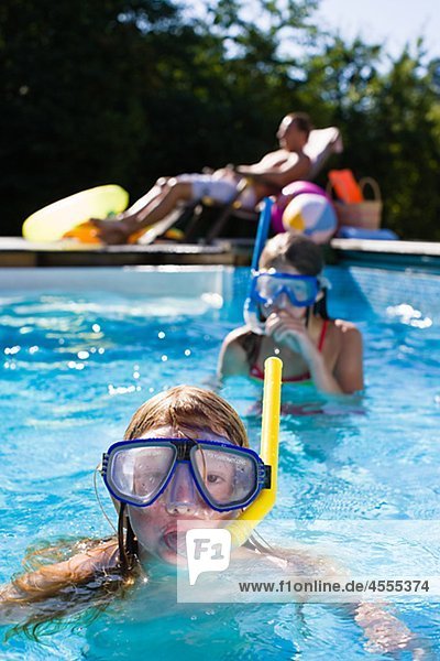 Children in scuba masks swimming in swimming pool