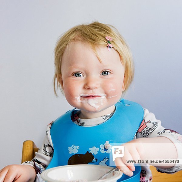 Baby mit Joghurt auf Gesicht  lächelnd