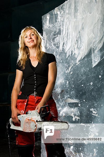 Artist standing with electric saw in front of ice block