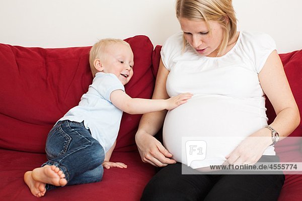 Junge schwangere Mütter Magen auf Sofa berühren