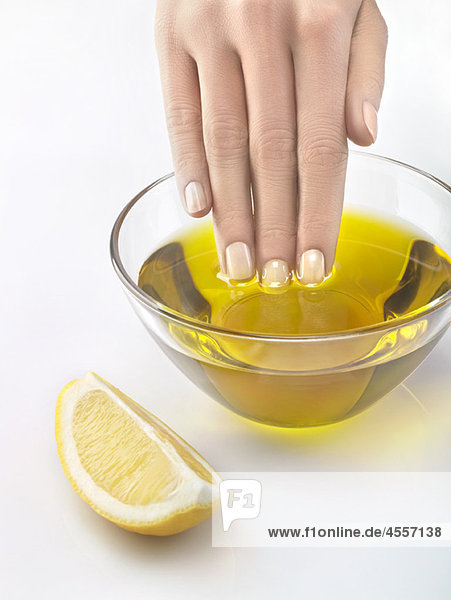 Nahaufnahme der Frauenhand in einer Schale mit Olivenöl