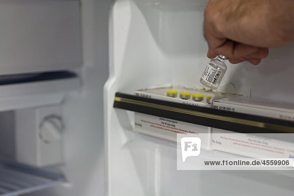 Medizinischer Fachmann beim Entfernen von Medikamentenfläschchen aus dem Kühlschrank