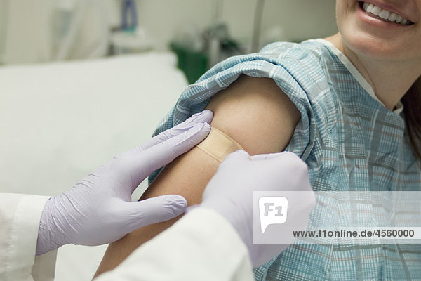 Arzt legt Klebebandage auf den Arm des Patienten auf