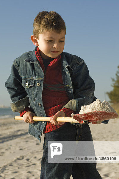 Junge beim Graben mit Schaufel am Sandstrand
