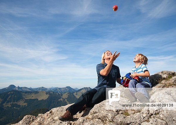 Deutschland  Bayern  Vater und Sohn (4-5 Jahre) spielen mit Ball auf Berggipfel