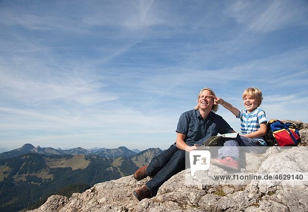Germany  Bavaria  Father and son (4-5 Years) looking away with map on mountain summit