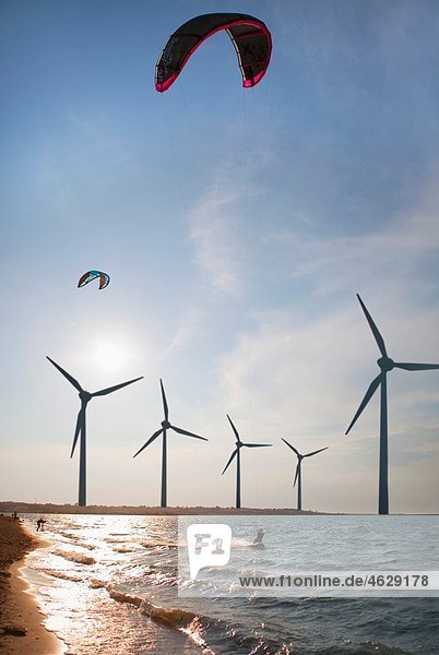 Kroatien  Zadar  Kitesurfer springen vor der Windkraftanlage bei Sonnenuntergang
