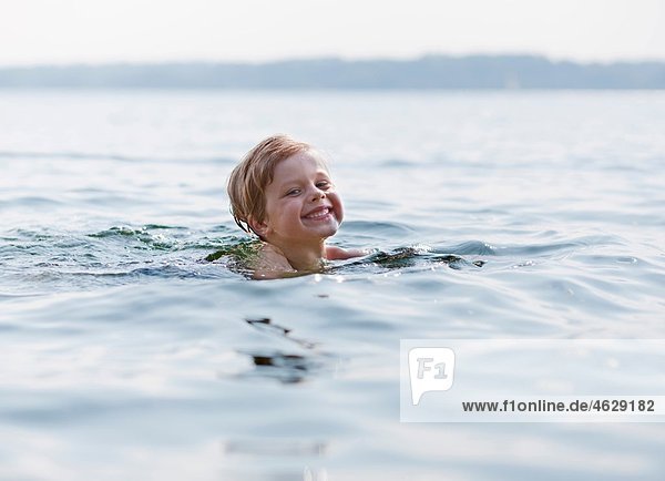 Junge im See schwimmend  lächelnd  Portrait