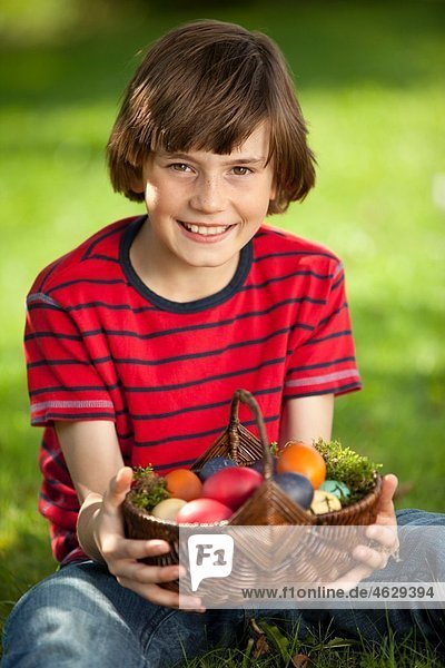 Deutschland  Junge (10-11 Jahre) lächelnd mit Ostereierkorb  Portrait