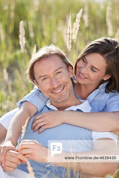 Mann und Frau  die sich auf der Wiese umarmen  lächelnd.