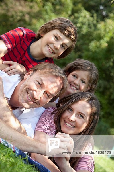 Deutschland  Bayern  Familie auf Gras liegend  lächelnd  Portrait