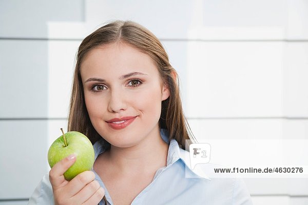 Junge Frau mit grünem Apfel  lächelnd  Portrait