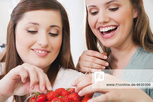 Young women sharing strawberry  smiling