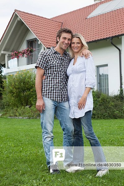 Deutschland  München  Paar vor dem Haus stehend  lächelnd  Portrait