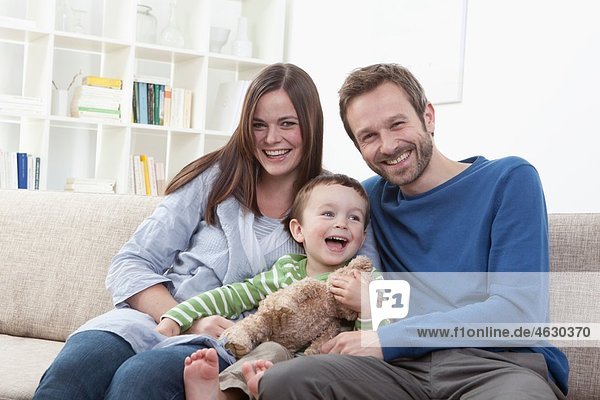 Deutschland  Bayern  München  Familie auf Sofa im Wohnzimmer  lächelnd