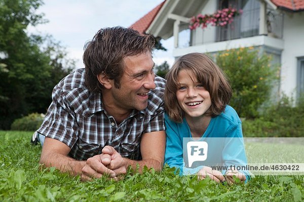 Deutschland  München  Vater und Sohn (10-11 Jahre) im Garten  lächelnd