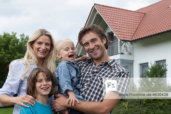 Deutschland  München  Familie vor dem Haus stehend  lächelnd  Portrait