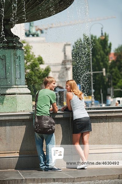 Junger Mann und junge Frau am Brunnen der Universität