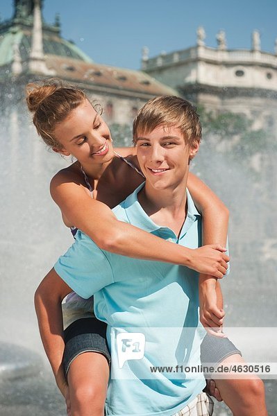 Young man carrying woman on piggy back