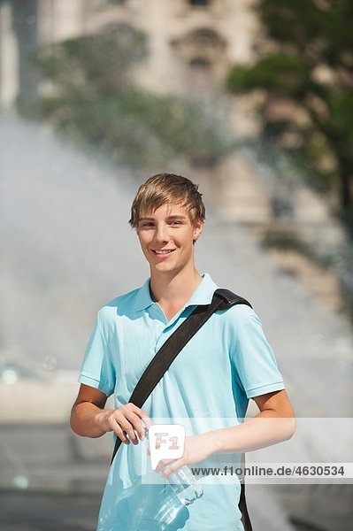 Junger Mann am Brunnen stehend  lächelnd  Porträt
