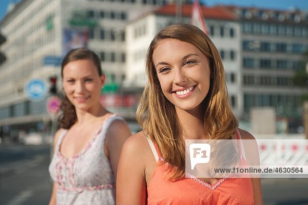 Young woman looking away with woman smiling in background