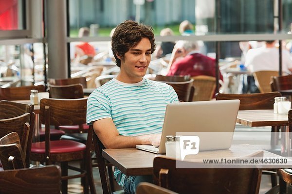 Young man using laptop in cafe