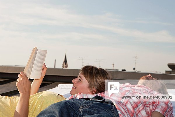 Deutschland  Bayern  München  Junges Paar entspannt auf dem Dach