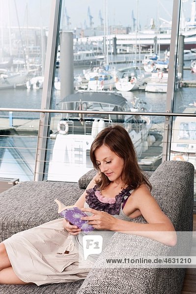 Woman reading book with harbor in background