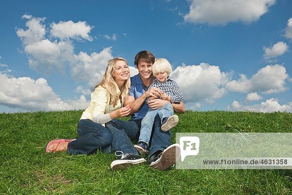 Deutschland  Köln  Familie auf Rasen sitzend  lächelnd