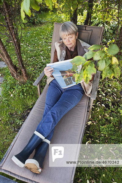 Frau sitzt im Garten und liest