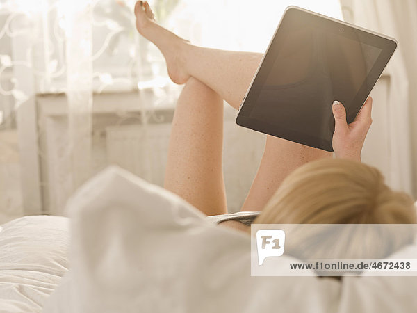 Young woman with Tablet PC in bed