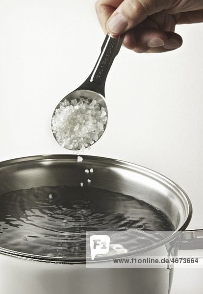 Salt being sprinkled into a pot of water