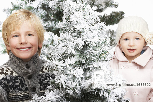 Brother and sister next to snowy trees